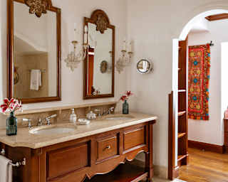 View of a large twin basin unit with a marble top and wooden base, and two wall-mounted mirrors, in a bathroom detail.