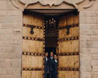 Three suited staff members open the grand principal doors of Palacio Nazarenas with big smiles.