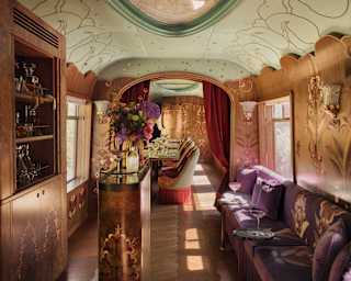 Looking through a luxurious carriage with a green-lipped ceiling, wood panelling and purple velvet banquettes.