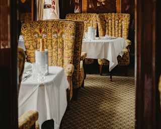 View from a doorway of two tables, laid with white clothes and Champagne coolers, flanked by gold-tone seats in the Ibis Car.