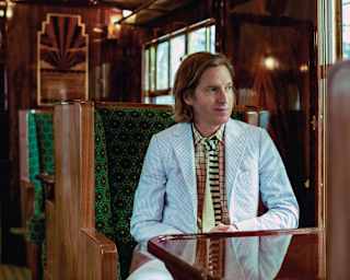 Filmmaker Wes Anderson sits at a French polished table in an art deco carriage and observes the world through the window