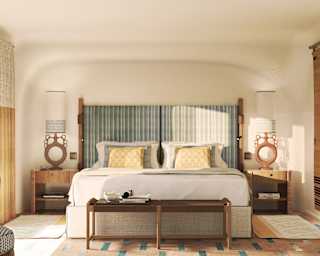 Looking at a bed in a Double Room with grey-teal headboard, flanked by artistic circle-structured ceramic reading lamps.