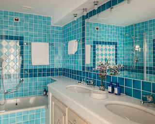 A bath wall features a boxed check pattern of blue-hue tiles in a Deluxe bathroom, reflected in the mirror above the basin.