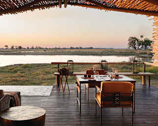 Shaded veranda with an elegant seating area and views across grasslands at sunset