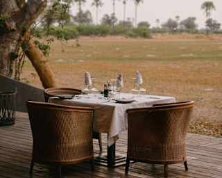 A dining table with three wicker tub chairs awaits guests at the edge of the restaurant deck overlooking the plains.