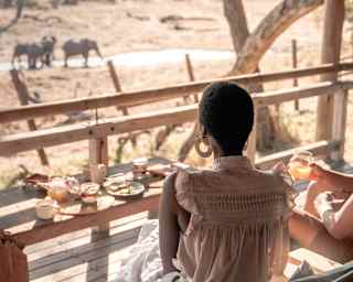 Guests eating breakfast on their private terrace watching elephants in the water just below