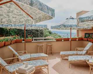On Spa Dior's terrace, four side tables, loungers and parasols, with furnishings in Toile de Jouy, soak up sun and views.