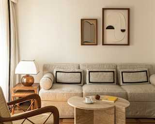 Simple wall art complements tranquil beige tones in a sofa and décor of Tramontana's Village View Junior Suite living area.
