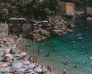 Swimmers gather in the turquoise waters of Bagni Fiore. Beach dwellers rest in the sun or shaded by lavender parasols