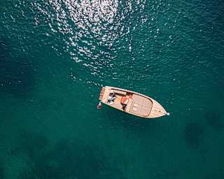 From above, deep bluegreen water surrounds a gozzo boat