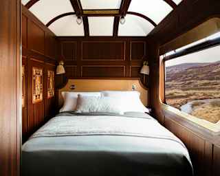 Looking into the Grand Suite bedroom where a bed sits between marquetry wall panels and a window on to the Scottish Highlands.