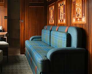 View of the living area of the Grand Suite where a blue tartan banquette sits up against exquisite, artistic wood panelling.