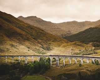 In a valley scene of plunging hillsides, the Royal Scotsman looks miniature as it crosses the span of the Glenfinnan Viaduct.