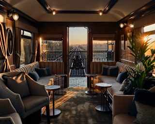 Tracks narrow with distance, seen beyond the Observation Car doors as sunset through windows stripes the low-lit interior.