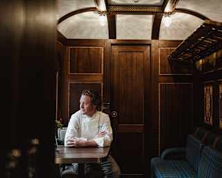 Chef Tom Kitchin sits in the Grand Suite looking out of the window, which illuminates his face in the warm wood surrounds.