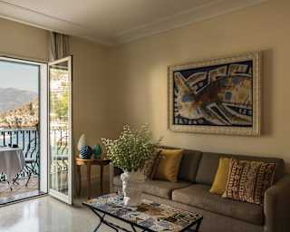 A trio of classic Sicilian pine cone ceramics in white, blue and green sit on a corner table. The balcony table is set for coffee