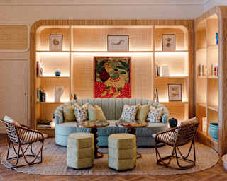 A grey sofa, two side tables and pairs of stools and chairs create a conversation area in front of backlit shelves of art.