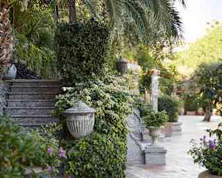 Italian garden with Grecian flower pots brimming with purple flowers and foliage