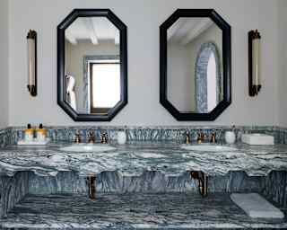Looking at a twin basin unit created in luxury grey-and-white Italian marble, with two mirrors and vanity lights above.