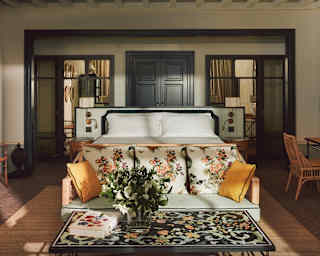 Sunlight brushes the botanic-print sofa and coffee table in view of a garden-theme Junior Suite with a bench, bed and desk.