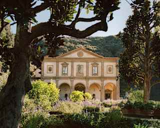 The Michelangelo-designed facade stands with palest pink walls amid a sea of green as lush hills climb up behind the gardens