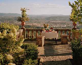 A lunch table on a rustic terrace overlooking Florence bakes in heat and romance, taken by Photographer François Halard.