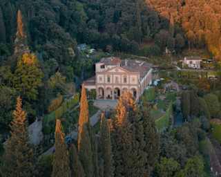 Sunset's rose-gold light brushes the tips of pencil pines and paints the hills behind Villa San Michele, nestled in woodlands.