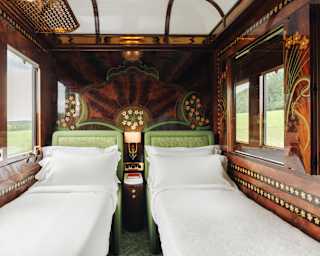 A La Campagne Suite with exquisite walnut wood marquetry with Art Deco floral inlays is set up for sleep with twin beds.