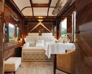 A Mountains Suite arranged for day with cool cream upholstery in the fold-away bed and carpet, with butter velvet chairs.
