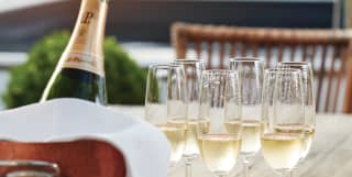 Bottle of Laurent Perrier champagne in a cooler beside filled flute glasses