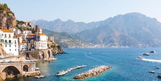 View across the Ravello bay with houses curving along the coastline and boats in the water