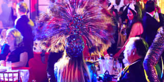 Guests sitting at circular party tables dressed in glamorous carnival outfits