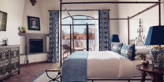 Elegant hotel room with ironwork four-poster bed and stone fireplace