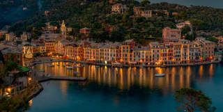 Portofino marina on a Christmas night, lined with glittering waterside restaurants casting reflections on the dark water.