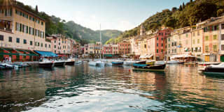 View from across the water of sailing boats anchored in Portofino harbour