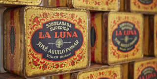 A display of pretty yellow, red and black tins containing the La Luna brand of sobresada cured sausage, spiced with paprika.