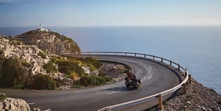 A motorcyclist enjoys the winding tarmac road that loops along Cap de Formentor to the lighthouse, affording vast sea views.