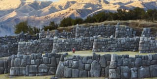 Rows of Inca stone walls with the Andean mountains in the background