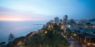 The shoreline of Lima at sunset with the twinkling cityscape beyond