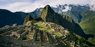 Stunning view of Machu Picchu, cradled in a mountain crest and surrounded by forested peaks towering over the Sacred Valley.
