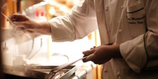 Close-up of a chef in chef whites cooking with a frying pan