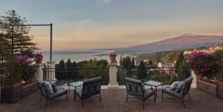 Villa terrace seating area with uninterrupted views of Mount Etna at sunset