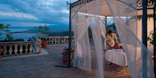 Massage table under an ornate wrought-iron pergola on an Italian villa terrace