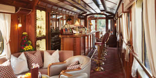 Wood-panelled bar carriage with leather banquette seating and a maroon carpet