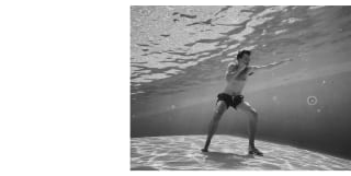 Black and white underwater image of actor Nicholas Hoult as he holds a boxing pose on the bottom of Hotel Cipriani's pool.
