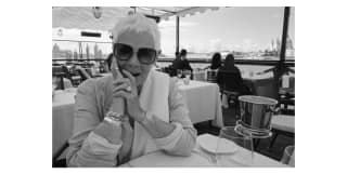 Black and white image of actress Dame Judi Dench in dark glasses at a Cip's Club table on the Canale della Giudecca.