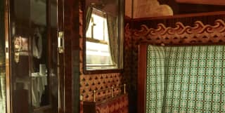 The sliding door, decorative woodwork and finely upholstered bench seat of a compartment in a restored period rail carriage