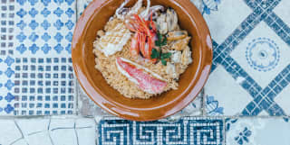A fresh seafood dish in a simple brown bowl on old blue-and-white ceramic tiles