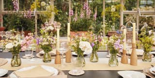 The Victorian glasshouse is set for a summer lunch, with vases full of Marguerites and Sweet Peas, candles and glassware