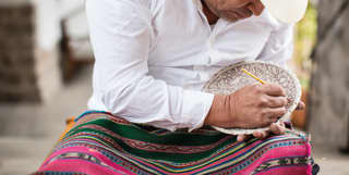 Close-up of artist Tater Vera hand painting a ceramic bowl